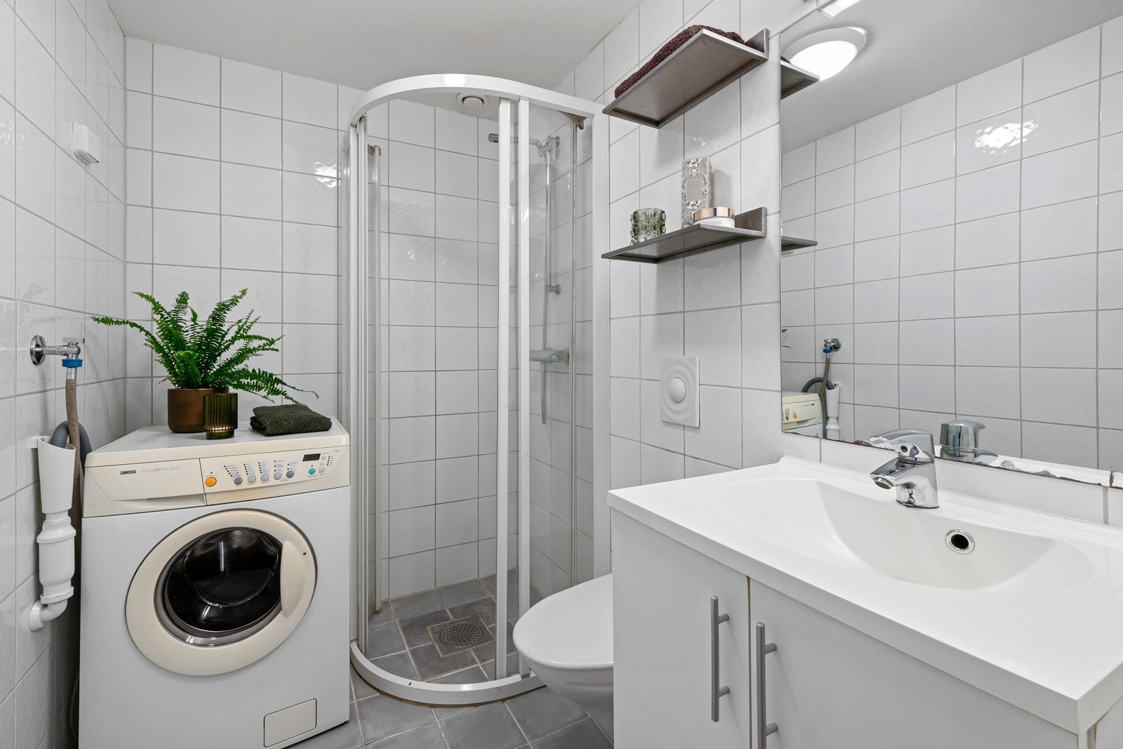 Badet i hybelen har hvite fliser på veggene og grå fliser på gulv med gulvvarme. Galleribilde