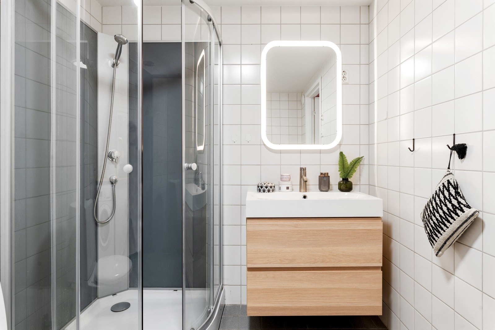 Videre er baderomsinnredningen bestående av speil med belysning, stikkonakter på vegg og gulstående toalett. Galleribilde