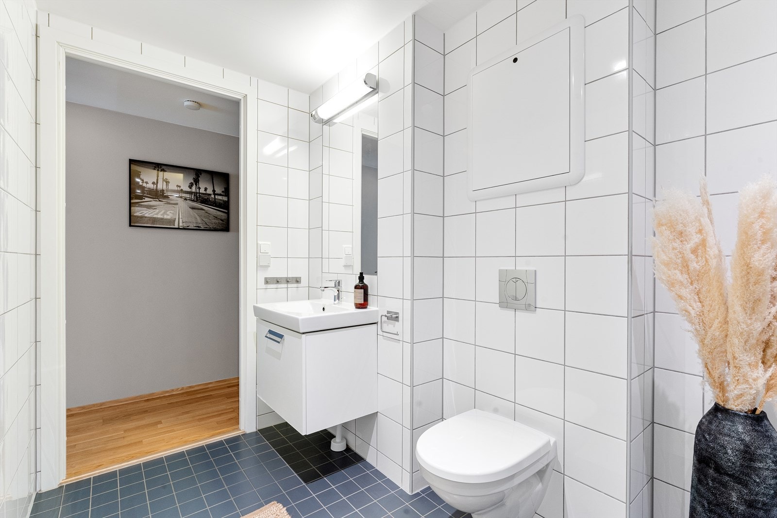 Badet består av servant med underskap, vegghengt speil, dusjhjørne med innfellbare dører og vegghengt toalett. Galleribilde