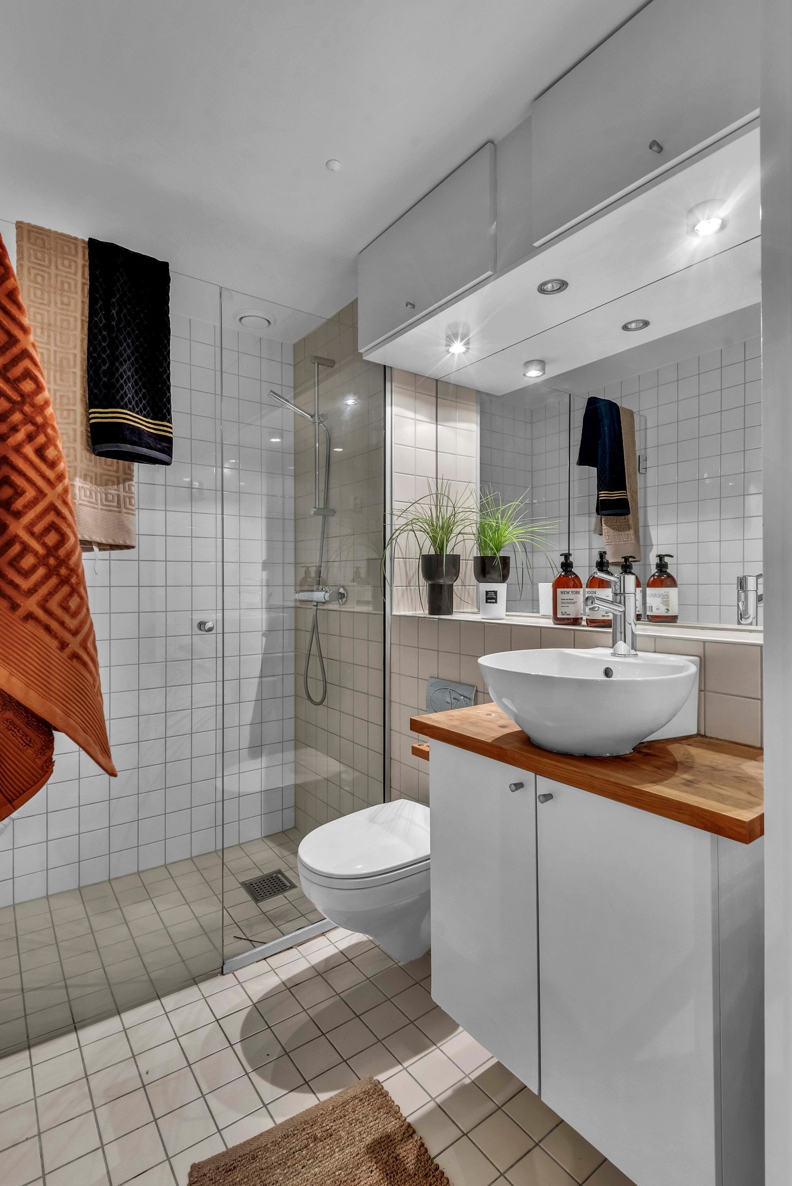 Av våtrom har leiligheten et pent bad som hovedsakelig har beige fliser på gulv og hvite veggfliser. Innredningen består av toppmontert servant på heltre benkeplate, hvitt servantskap og speil med innfelte spotlights i kasse over Galleribilde