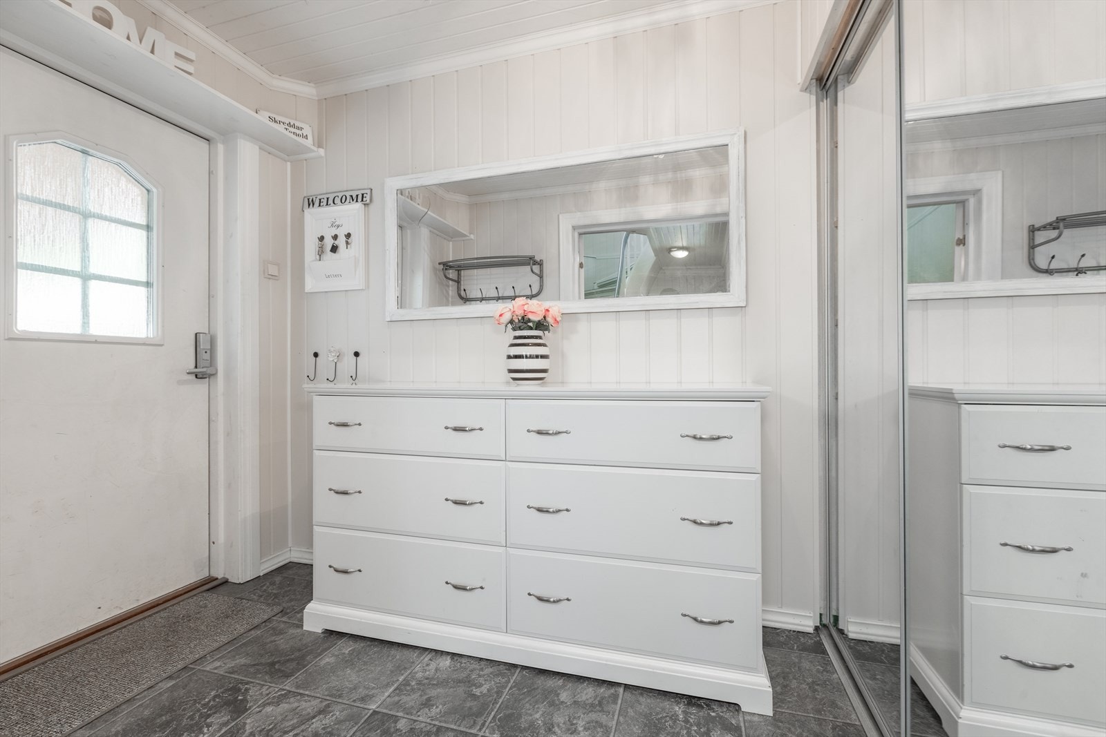 Vidare kjem ein inn til entré som er innreia med praktisk og romsleg skyvedørsgarderobe Galleribilde