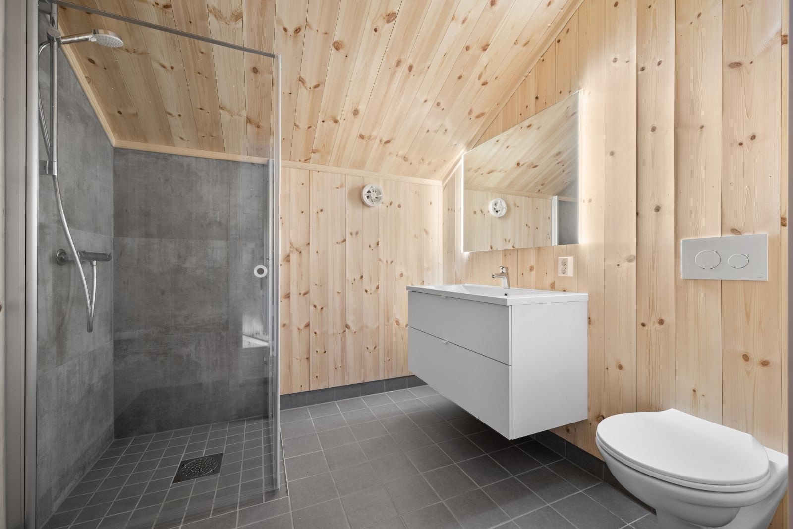 På badet er det en fin kombinasjon av furupanel og delikate, grå fliser. Galleribilde