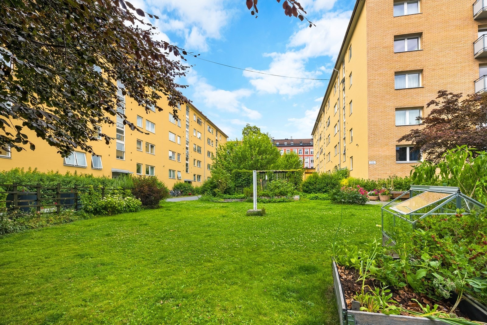 Pent opparbeidet fellesareal i kvartalbebyggelse med asfalterte arealer, steinbelagte arealer, gressplen, beplantning, trær, sittegrupper m.m. Galleribilde