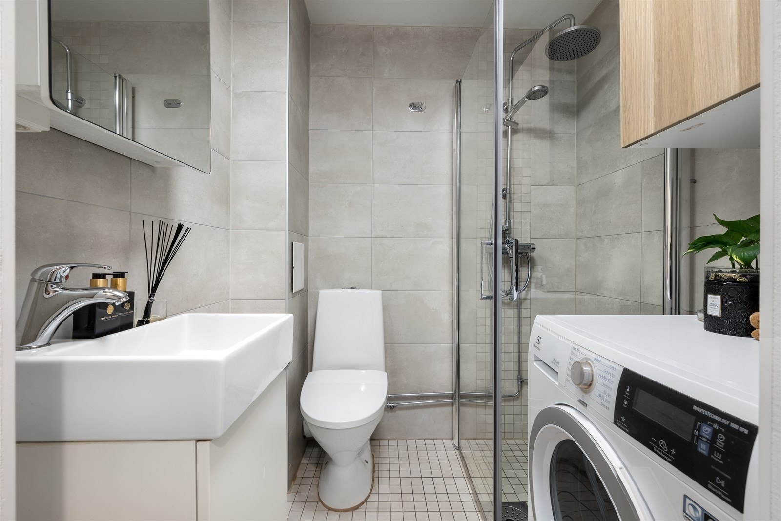 Flislagt, delikat bad med baderomsinnredning bestående av benkeskap med glatte fronter. Galleribilde