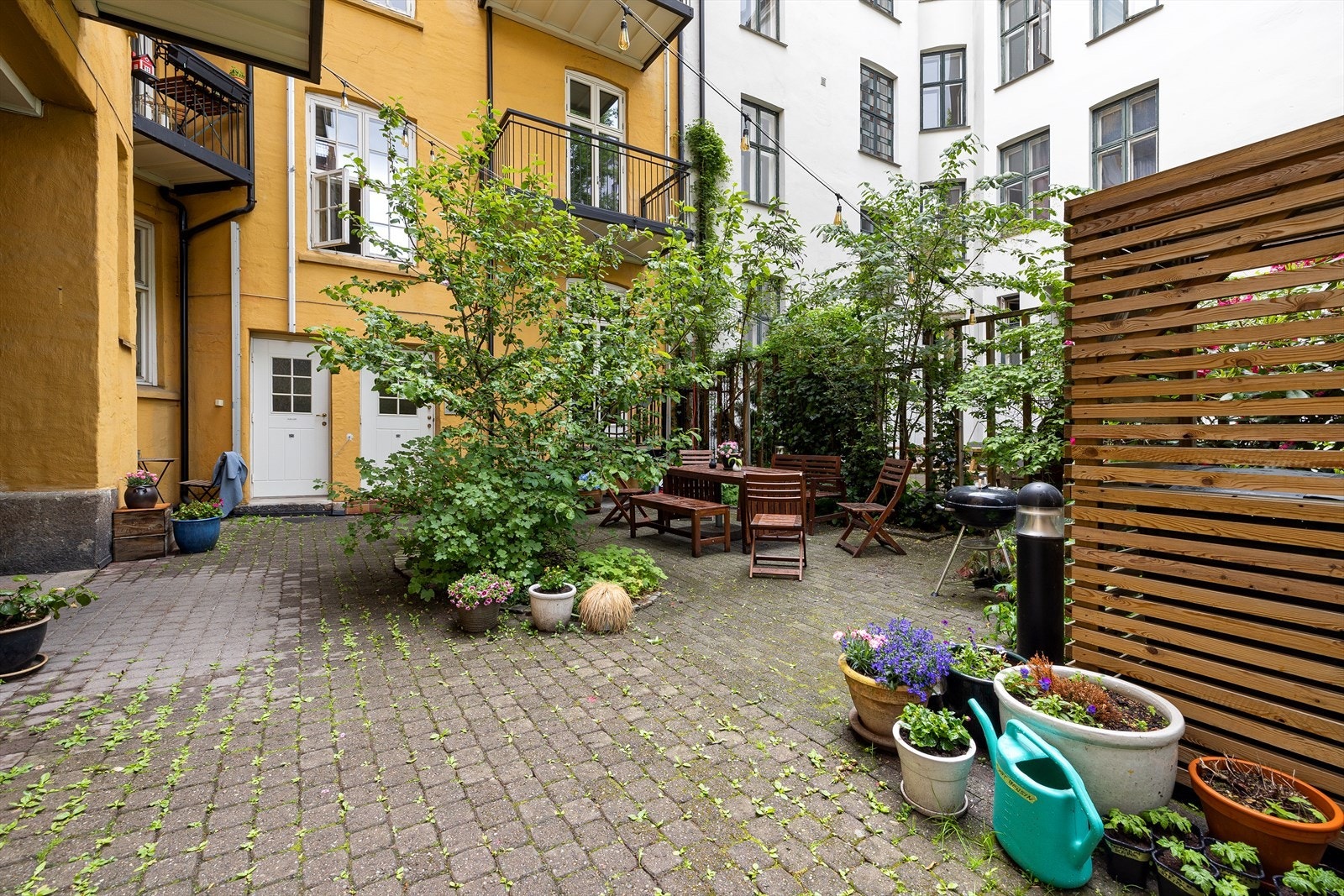 Hyggelig og rolig bakgård opparbeidet med sittegrupper, busker og blomster. Galleribilde