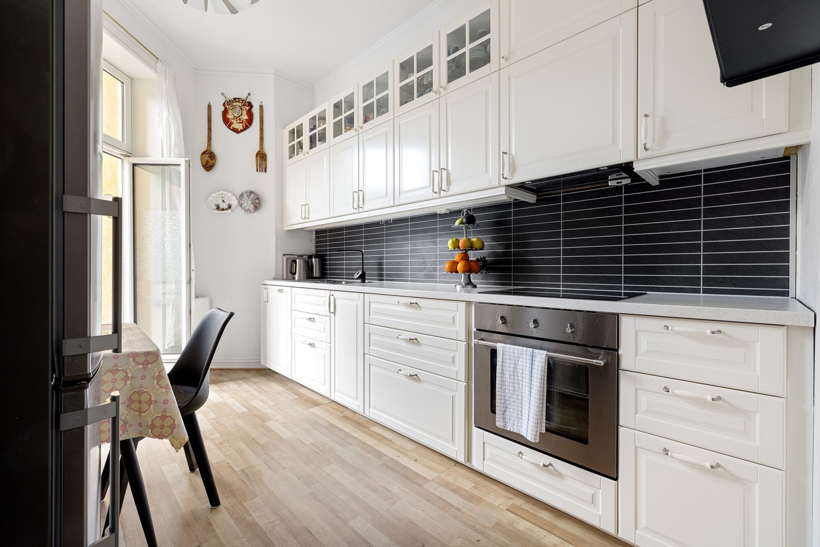 Lyst kjøkken med over og underskap med påmontert profilerte fronter. Det er godt med benkeplass og skapplass. Galleribilde