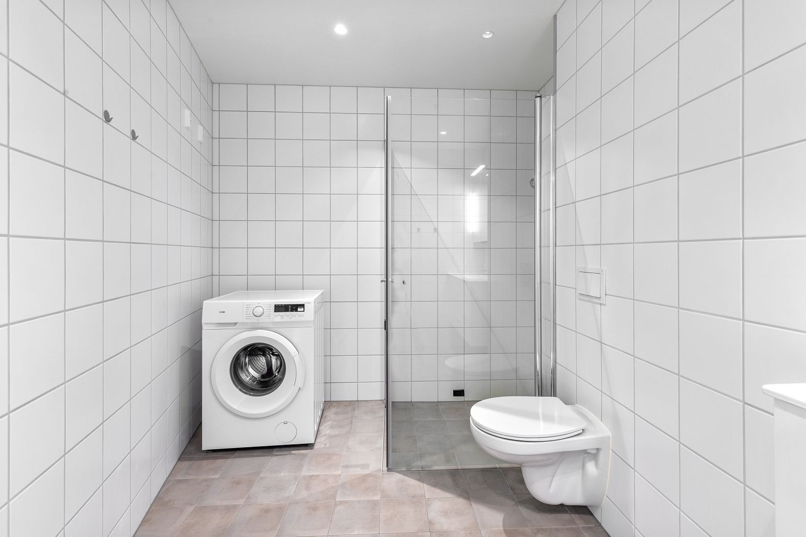 Badet er innredet med vegghengt toalett, dusjnisje og opplegg til vaskemaskin. Galleribilde