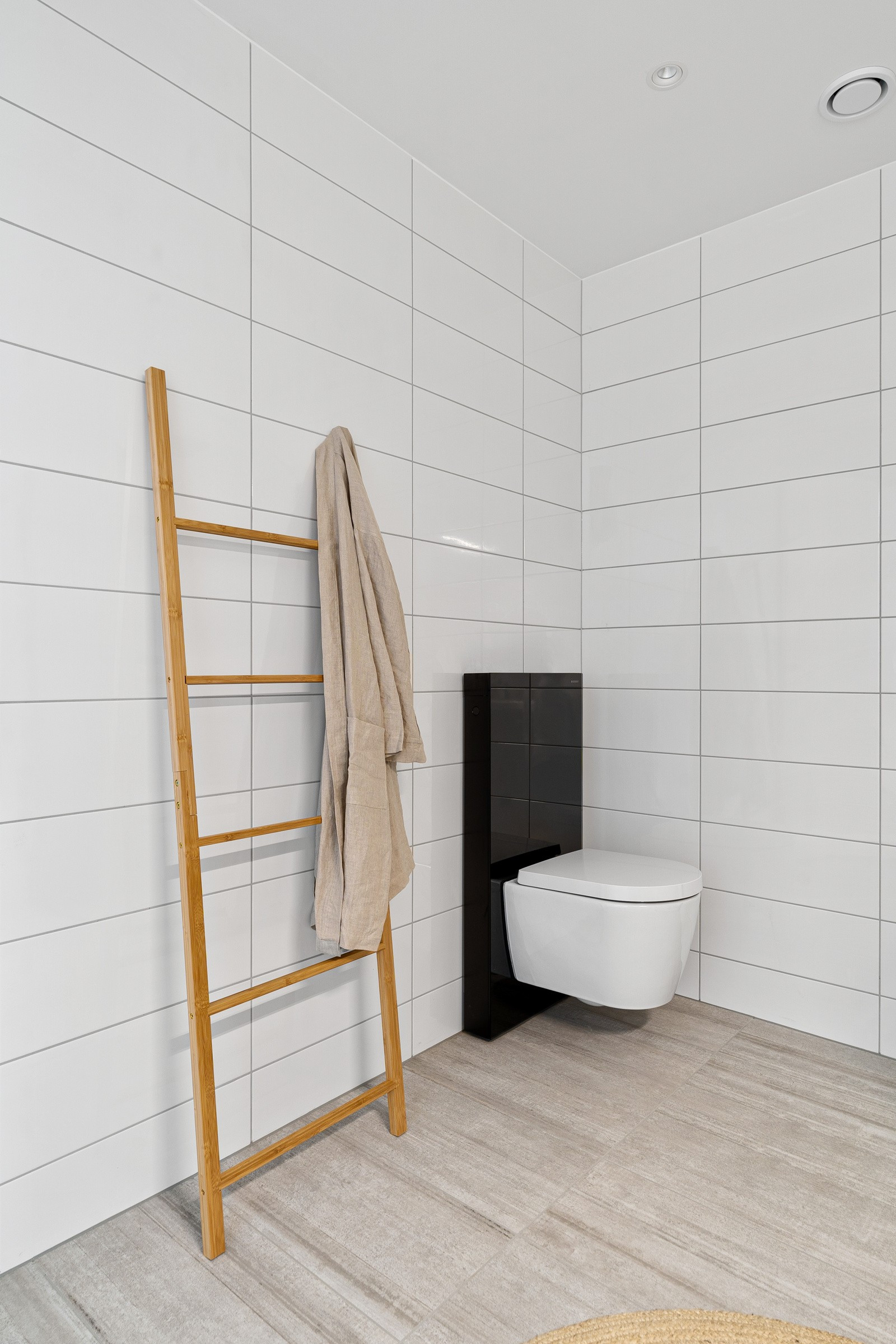 Flislagt bad med 20x50 fliser på vegg og grå 30x60 fliser på vegg.