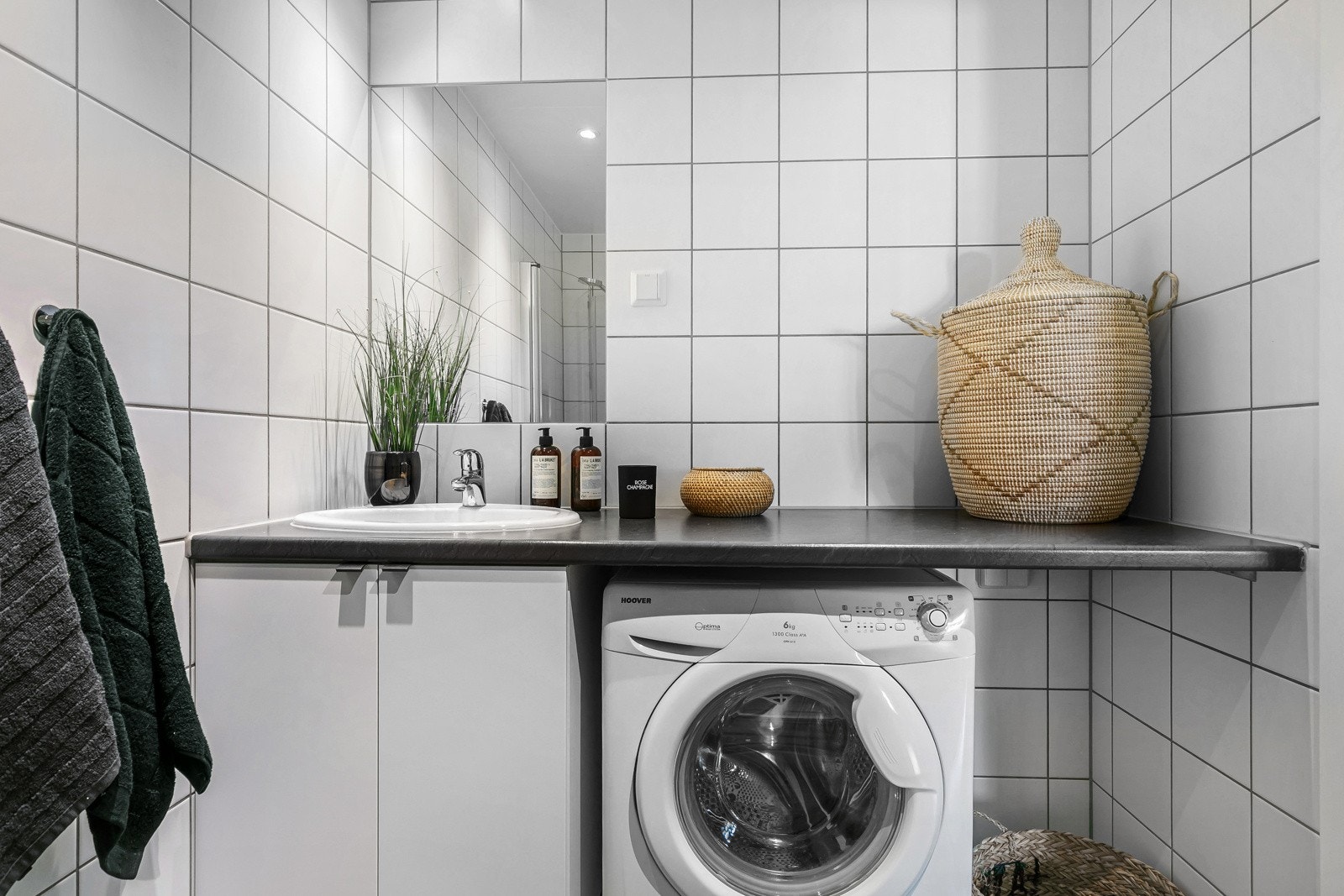 Baderommet inneholder dusjhjørne med buende svingdører av herdet glass, sluk, termostatstyrte varmekabler, servant på benkeplate, servantskap, speil på vegg og veggmontert toalett. Galleribilde