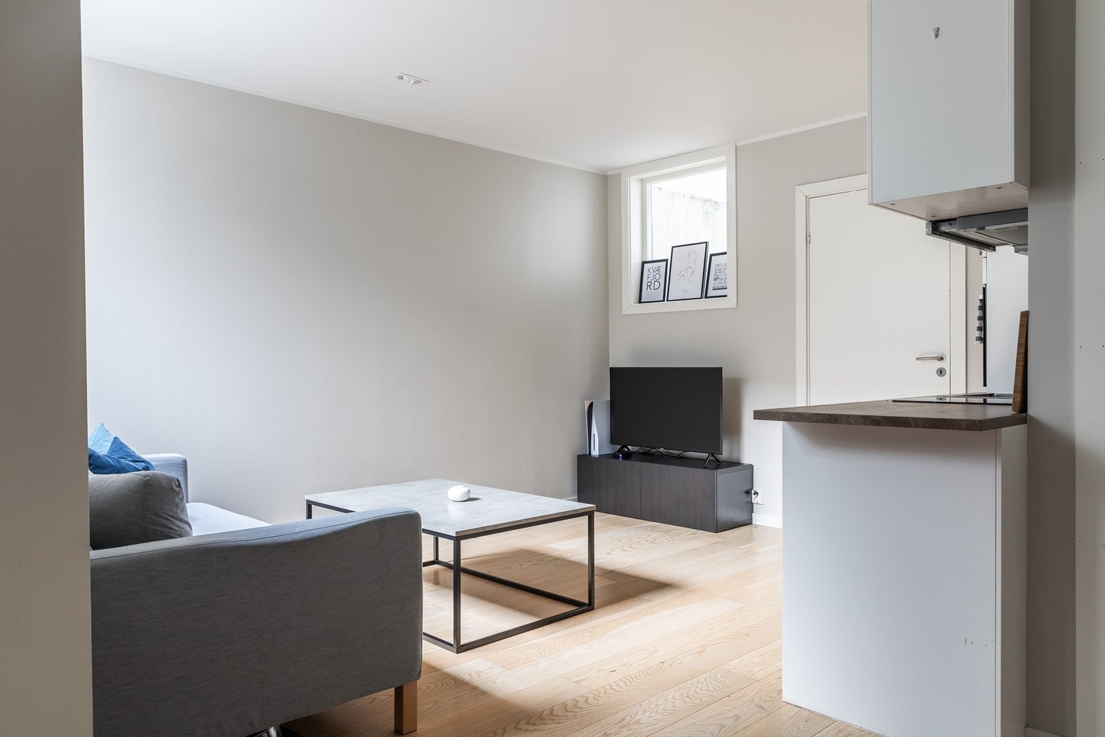 Lys stue med åpen kjøkkenløsning, inngang til innredet rom Galleribilde