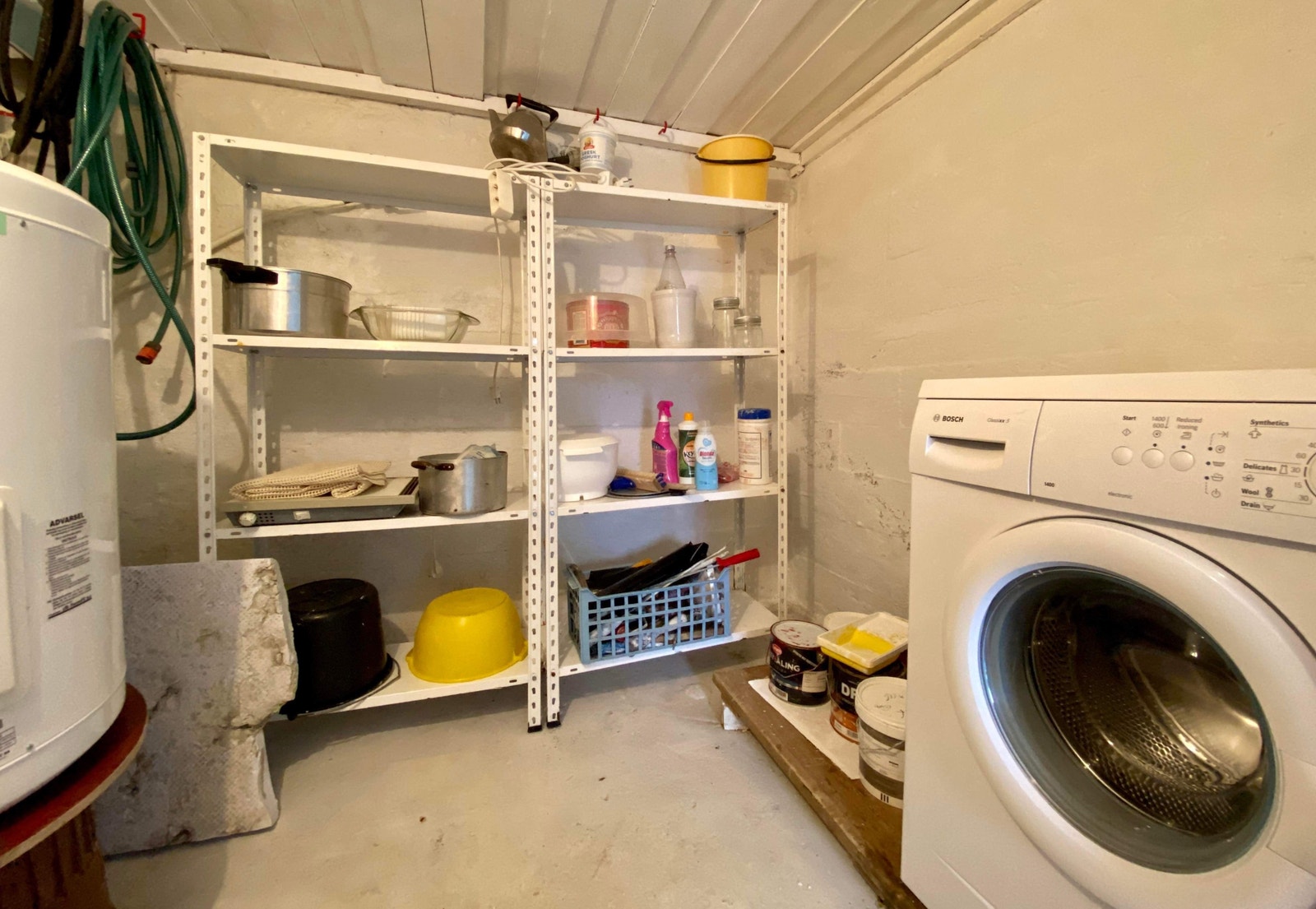 Kjellerbod med vaskemaskin, varmtvannstank og hyller Galleribilde