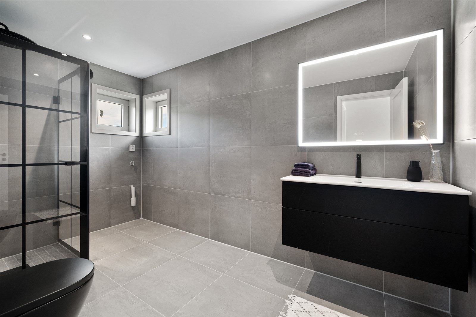 Lekkert helfliset bad utført i 2022 - Badet har 60x60 fliser på gulv og vegger. Badet har nedsenket dusjnisje med fliser i størrelse 7x7. Galleribilde