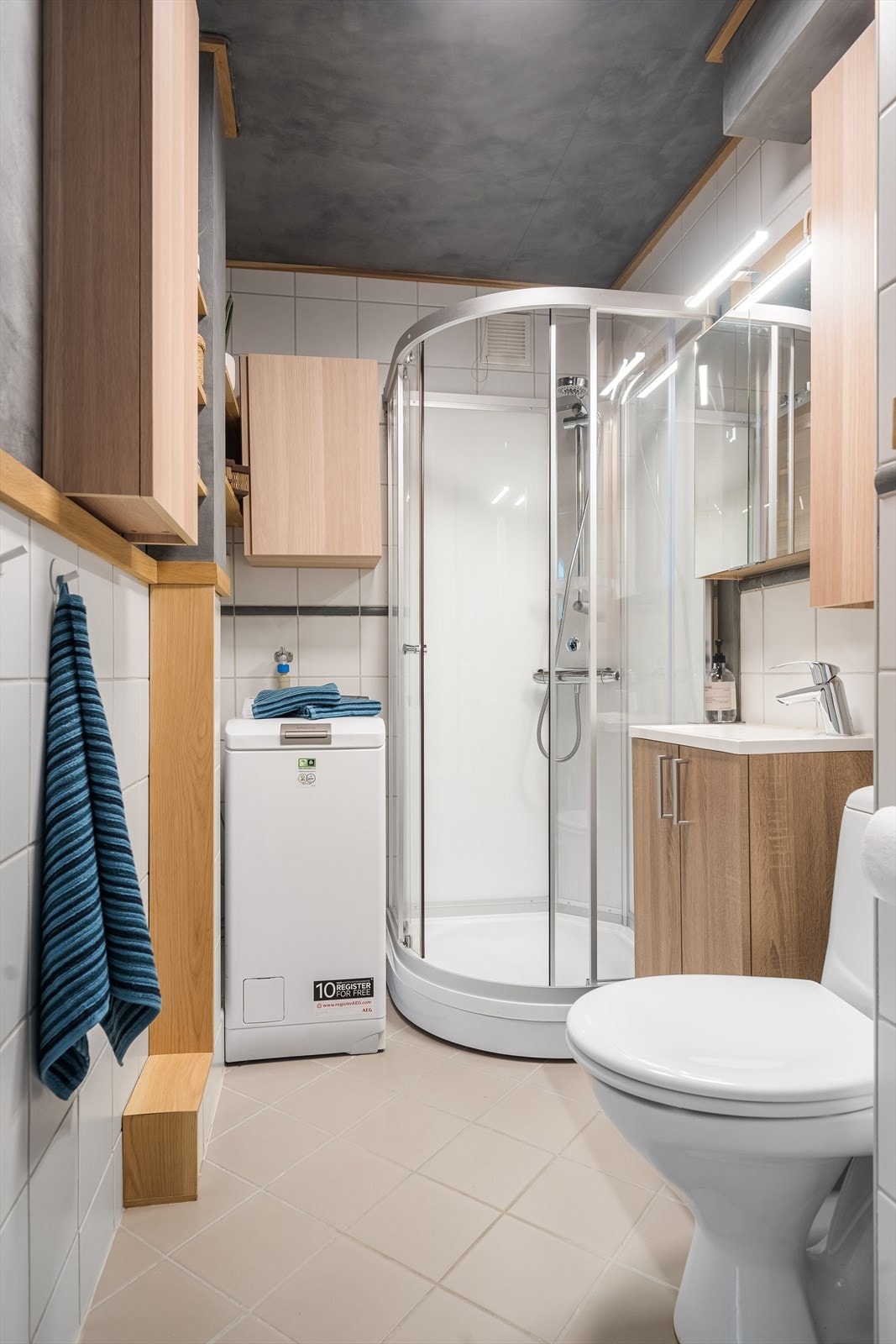 Flislagt bad med opplegg til vaskemaskin, dusjkabinett og servant med underskap Galleribilde