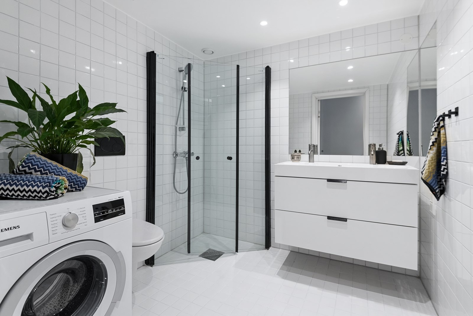 Baderom | Baderommet er utstyrt med dusjhjørne, vegghengt toalett, servant med underskap og opplegg til vaskemaskin. Galleribilde