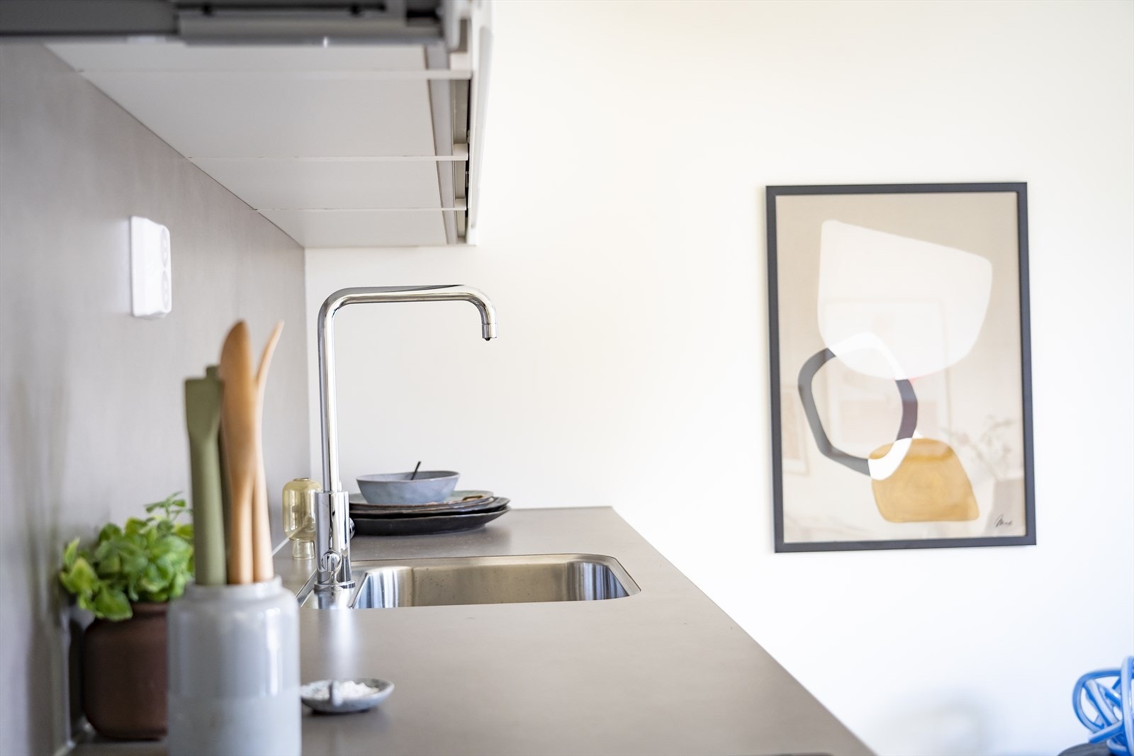 Lyst kjøkken med hvite, folierte fronter og benkeplate med underlimt vaskekum og ett-greps blandebatteri Galleribilde