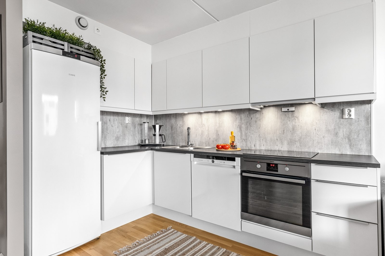 Hvit, glatt innredning med skuffer og skap, samt laminerte benkeplater. Galleribilde