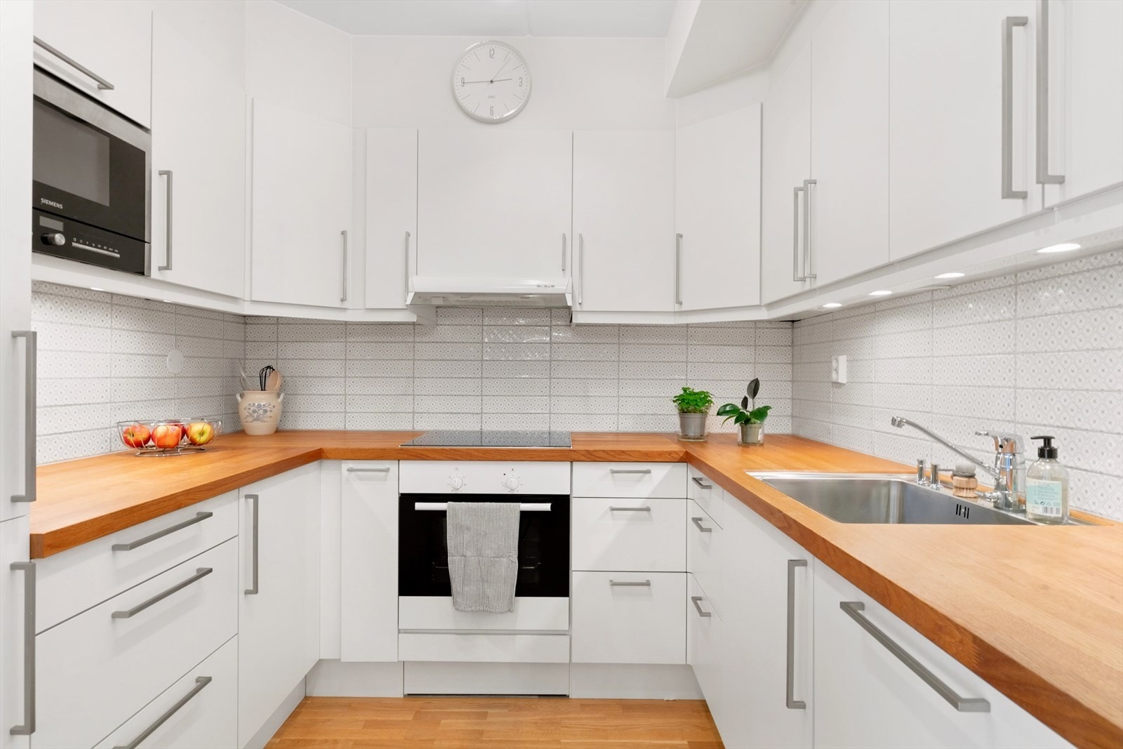 Moderne HTH-kjøkken med hvitevarer som mikrobølgeovn, stekeovn, koketopp, oppvaskmaskin og kjøl- og fryseskap. Galleribilde