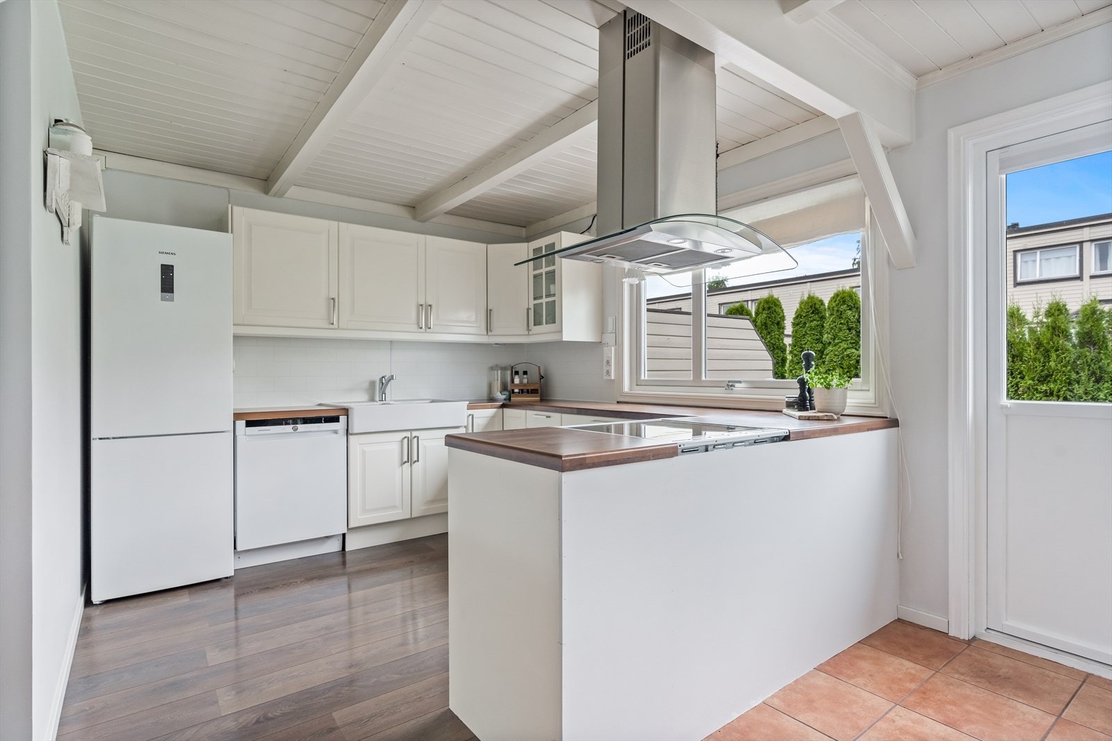 Kjøkkeninnredningen fremstår som tidløs og klassisk med profilerte, hvite fronter, og valnøttfarget laminat benkeplate. Galleribilde