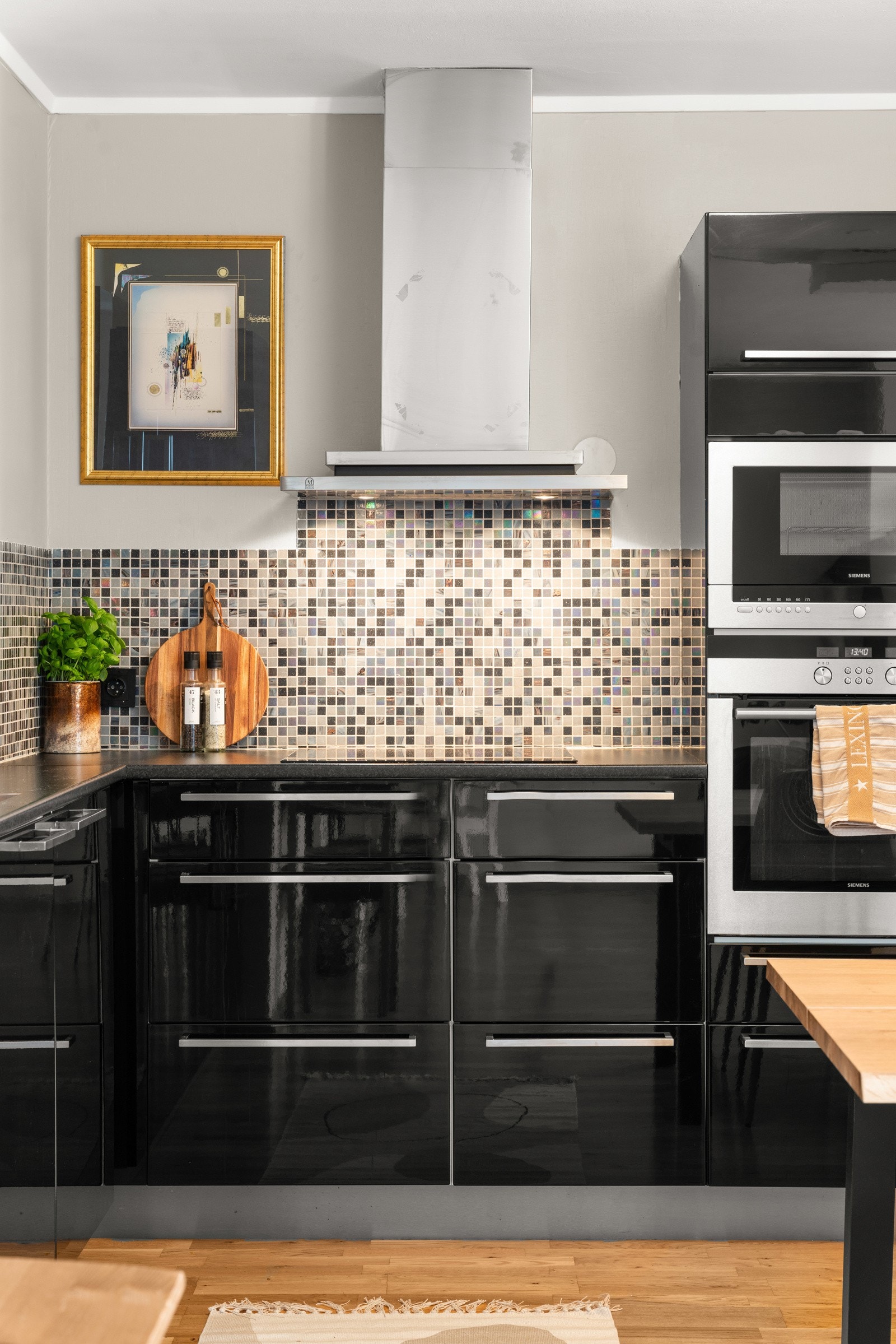 Moderne kjøkkeninnredning med slette, sorte fronter i høyglans og benkeplate i laminat. Galleribilde