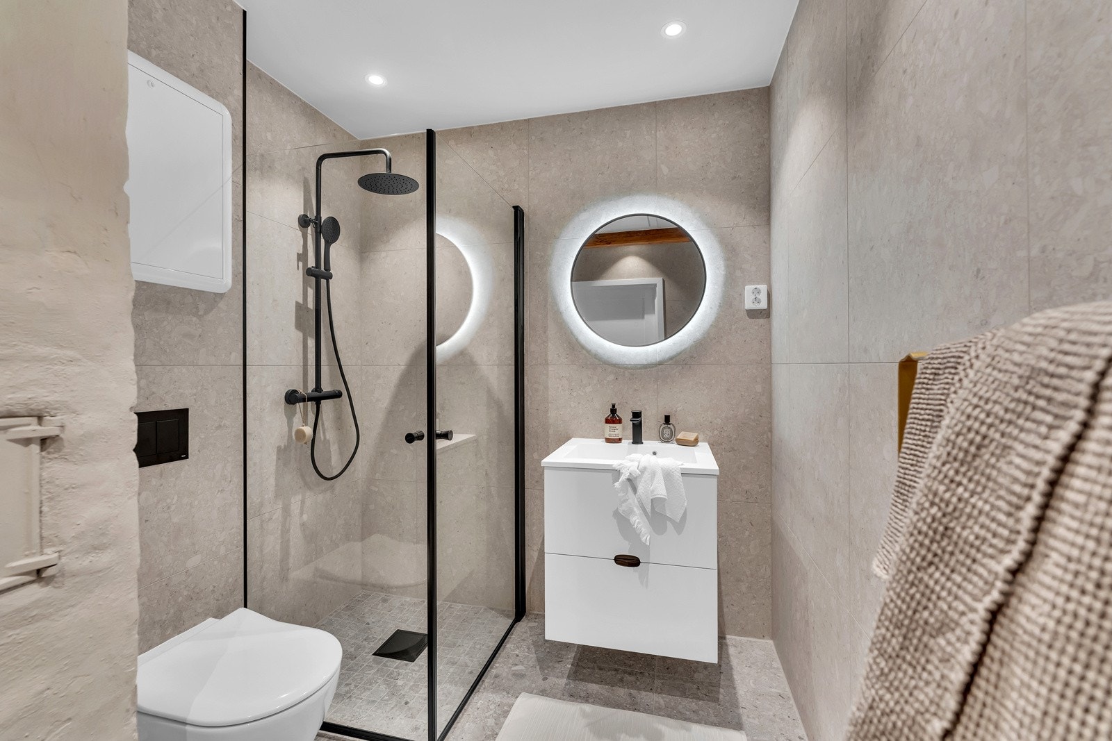 Lekkert baderom med store italienske fliser på overflater, Kvik baderomsinnredning, speil med integrert lys i delikat design, romslig dusjhjørne(90x90) og vegghengt toalett fra Villeroy&Bock. Innfelte downlights i himling og varmekabler i gulv. Galleribilde