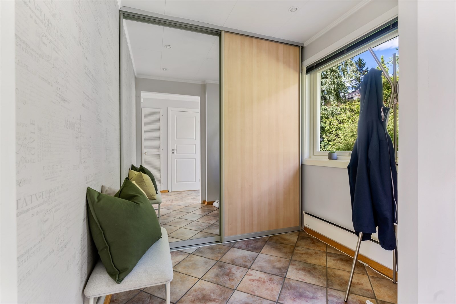 Adkomst fra entreen til et romslig omkledningsrom med skyvedørsgarderobe. Galleribilde