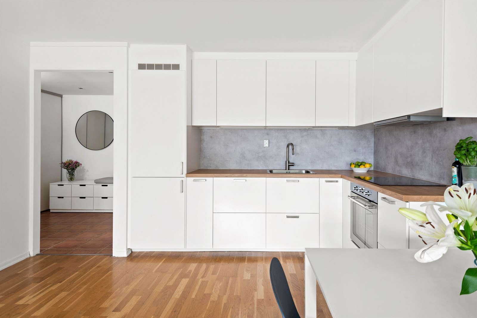 Det er lys under overskap, kum med ettgreps blandebatteri, laminert benkeplate, kullfiltervifte over integrert koketopp/ovn, integrert kjøl/frys og integrert oppvaskmaskin Galleribilde