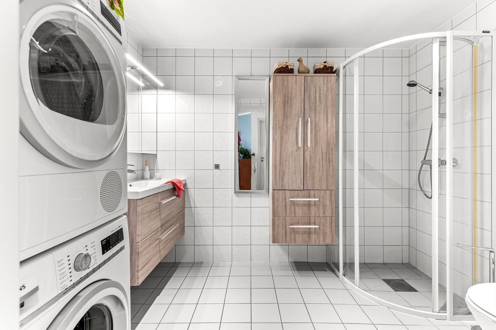 Badet er innredet med vegghengt servantskap i slett utførelse, ovenpåliggende servant med ett-greps armatur, og speilskap med belysning over servant. Galleribilde