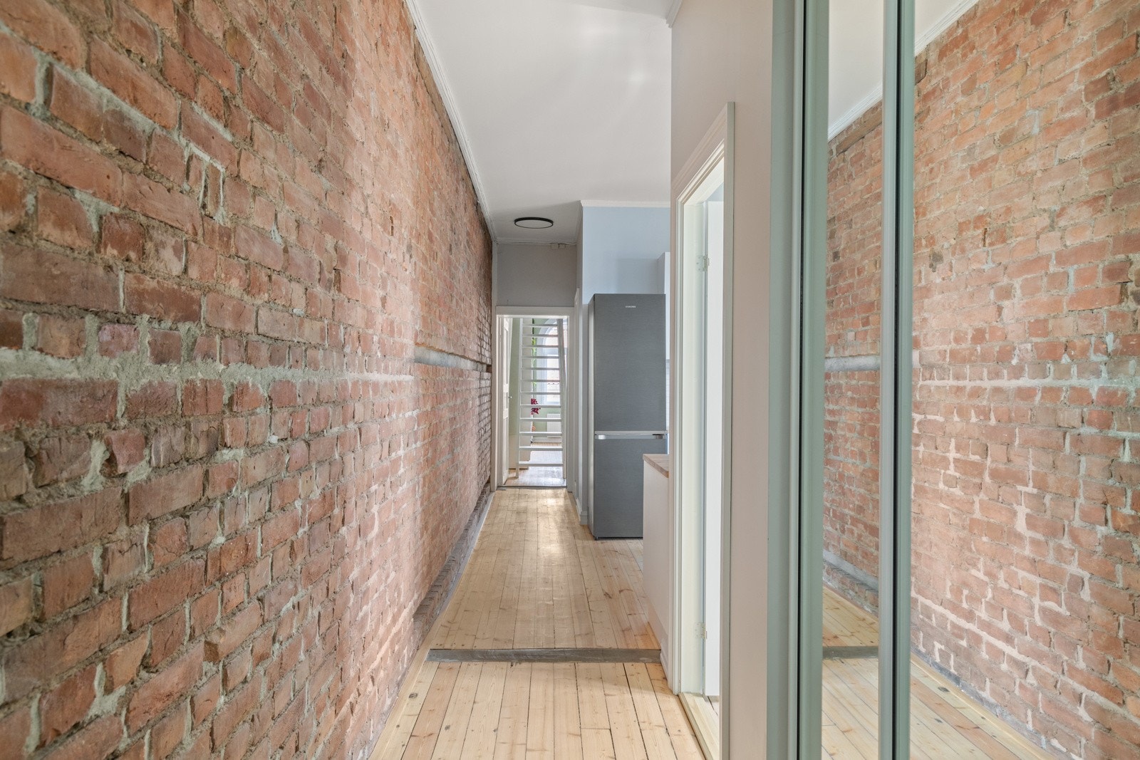 En entré med god lengde og imponerende takhøyde, samt nyslipte tregulv og rålekre teglsteinsdetaljer skaper en trivelig og innbydende følelse. Galleribilde