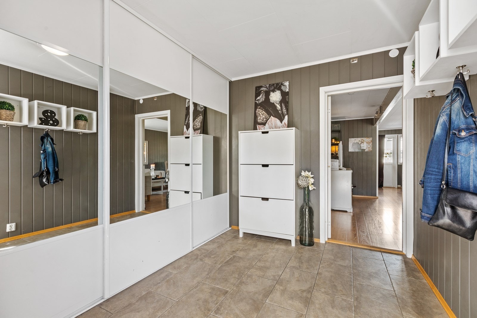 Romslig entré med fliser på gulv, og rikelig med oppbevaringsplass i skyvedørsgarderobe Galleribilde