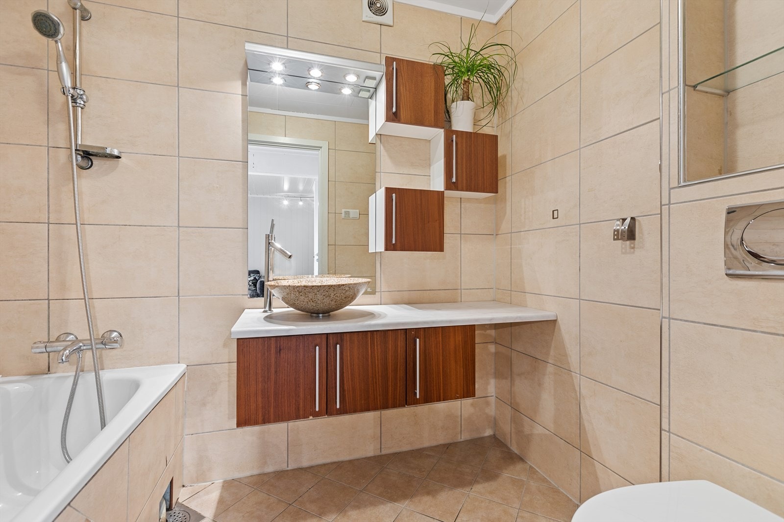 Badet i 2. etasje er pent innredet med sandfargede fliser på gulv og vegger, med underliggende varme i gulv Galleribilde