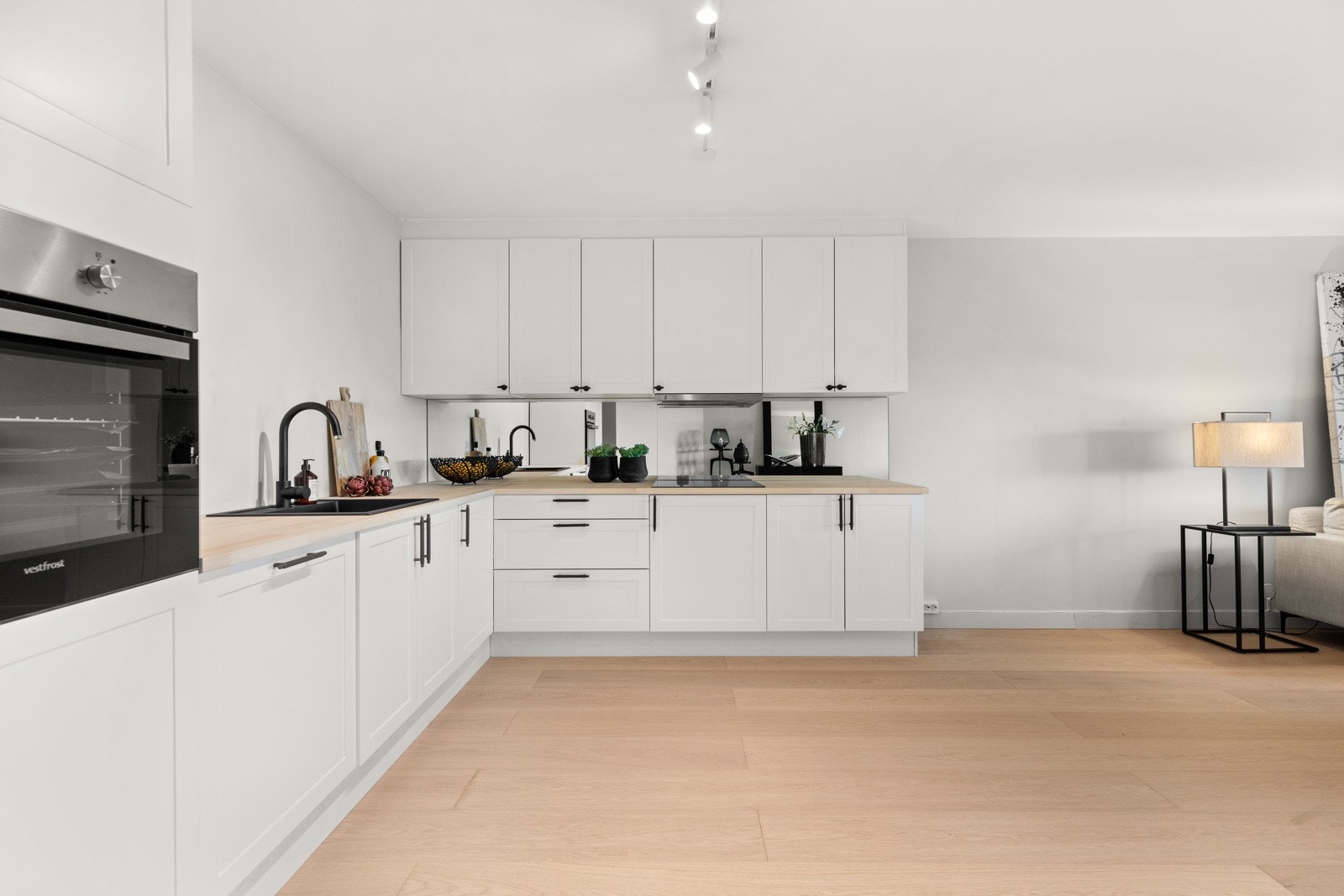 Det er speil på veggen over kjøkkenbenken, noe som skaper et moderne uttrykk og en god romfølelse Galleribilde