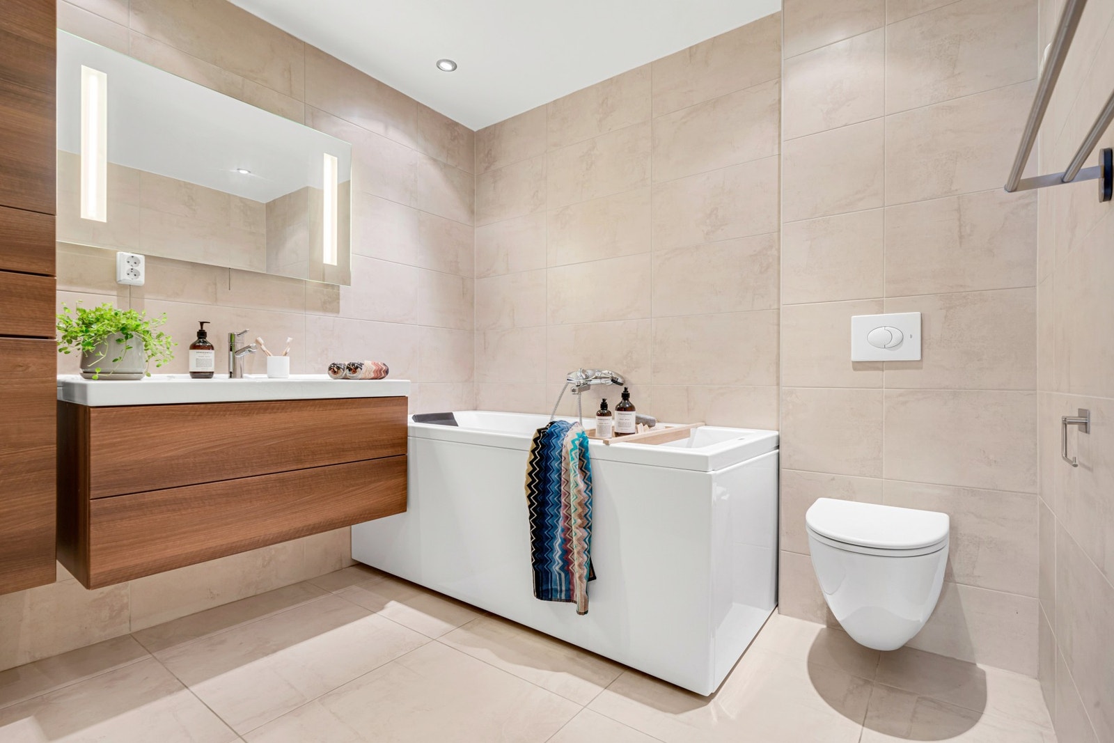 Delikat og flislagt bad fra 2010 med moderne innredning, badekar, vegghengt WC og dusjnisje. Galleribilde