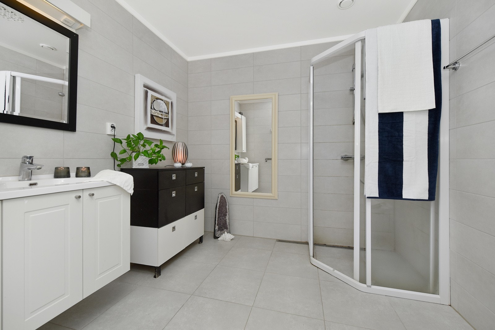 Begge baderommene har lys grå fliser på gulv og vegger. Galleribilde