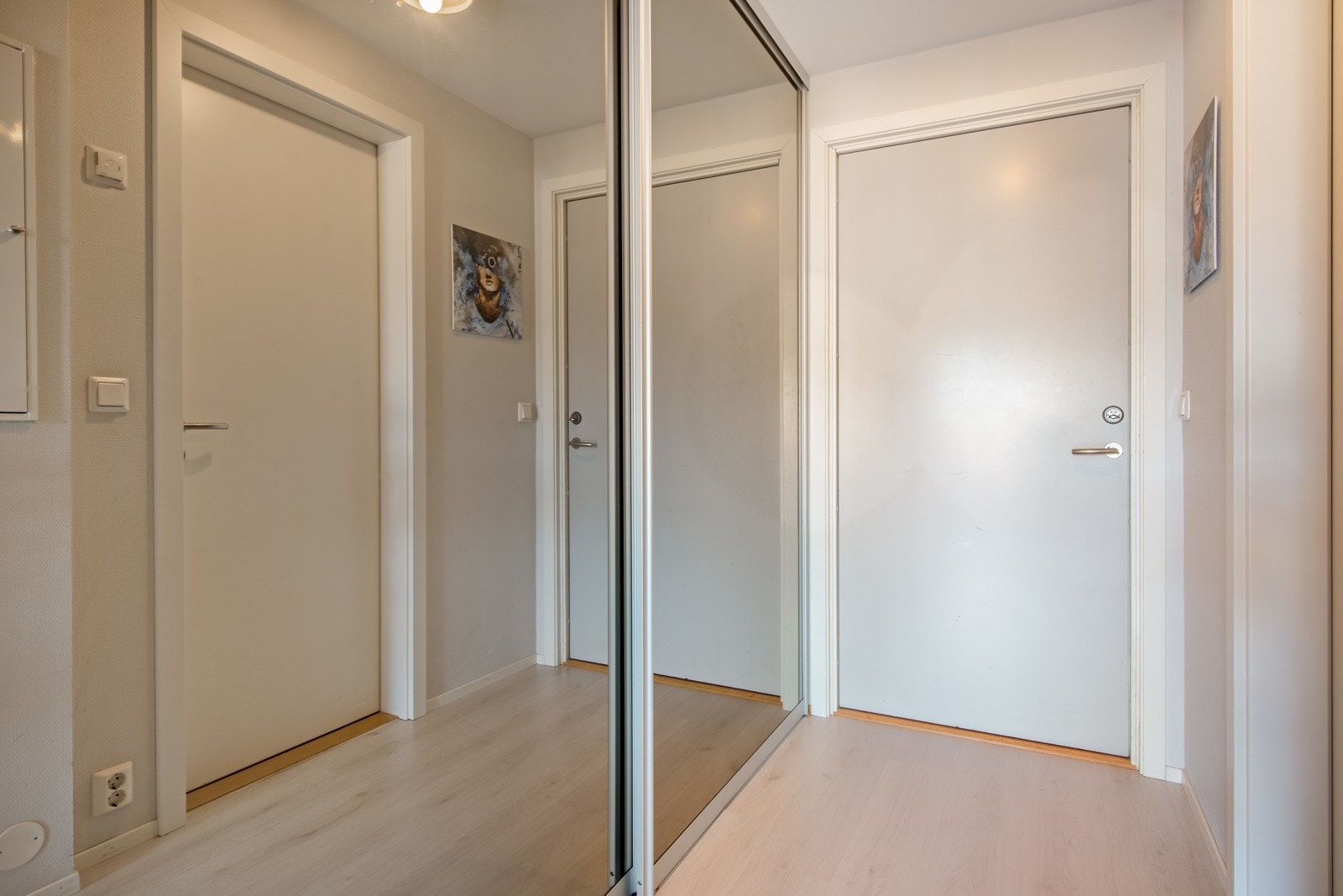 Entréen har enstavs laminat på gulvet, lysmalte vegger og en romslig skyvedørsgarderobe med speilfronter. Galleribilde