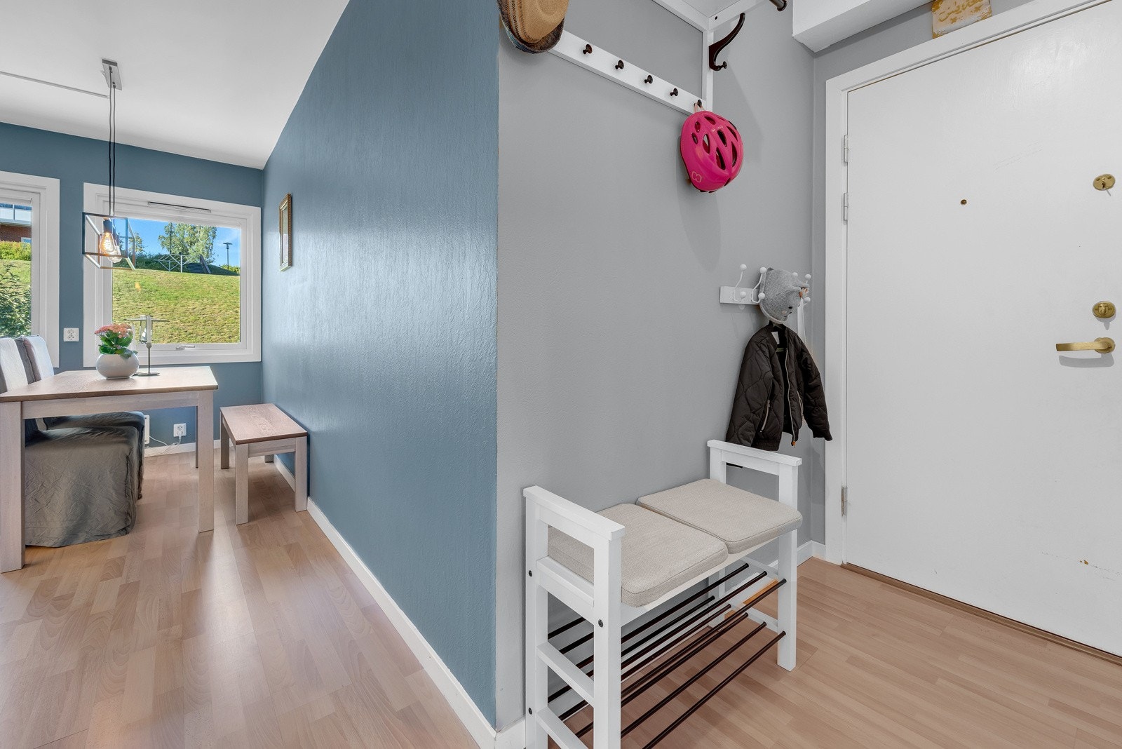 Entré/gang, kjøkken og stue har lyst laminat gulv om pene malte overflater. Videre fra entréen mot kjøkkenet. Galleribilde