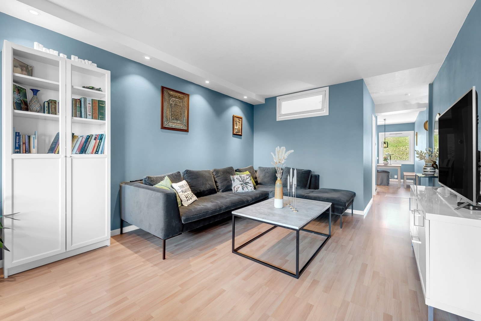 Boligens oppholdsrom er meget pent med behagelige blåmalte overflater og lyskasser med downlights! Galleribilde