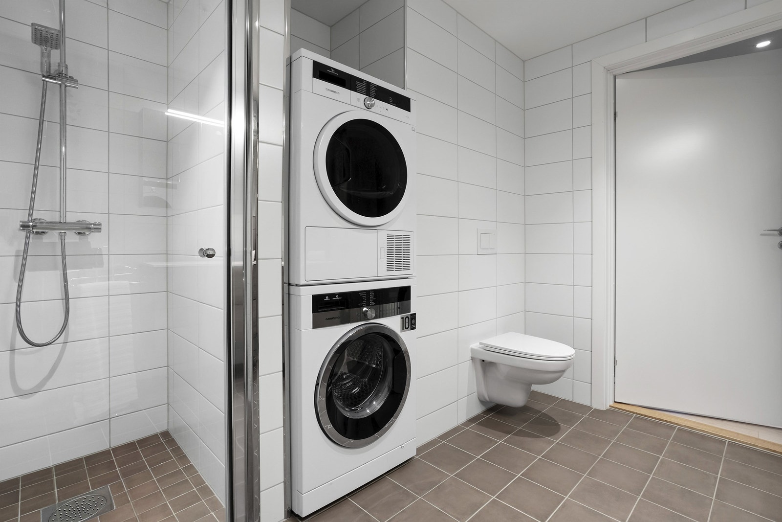 Videre er badet utstyrt med med vegghengt toalett, pen baderomsinnredning og overspeil med integrert lys og en smart løsning for vaskemaskin og tørketrommel. Galleribilde