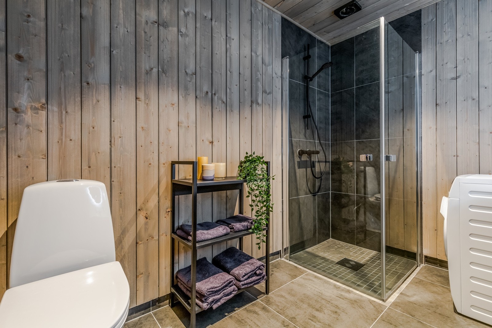 Baderom i første plan. Dusjhjørne, wc, vask og opplegg for vaskemaskin. Galleribilde