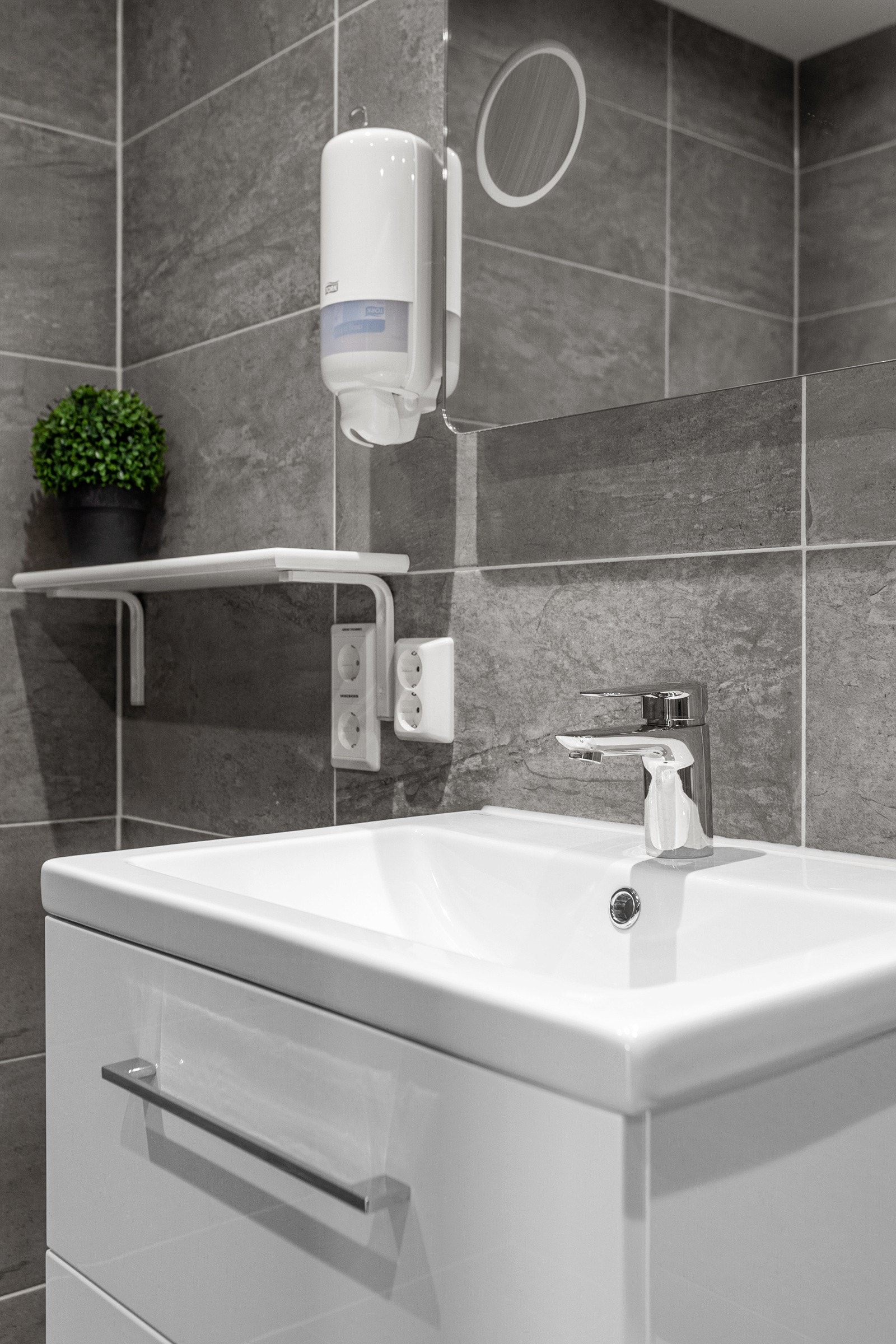 Badet er innredet med servant på innredning, toalett og dusjhjørne med glassdører. Galleribilde