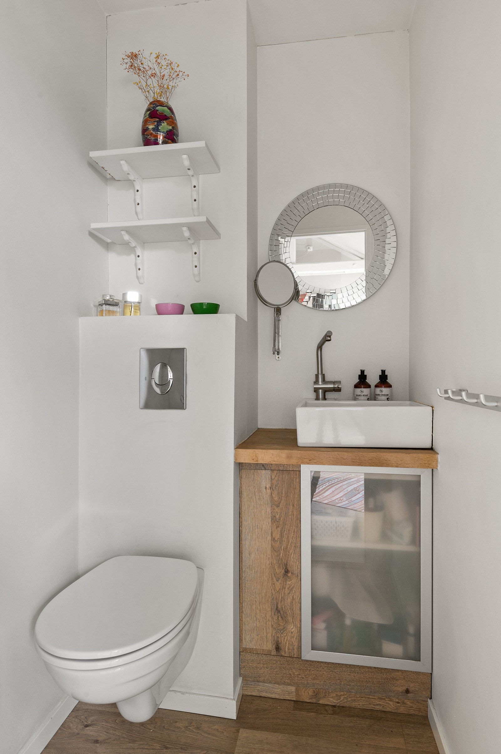 Toalettrom med vegghengt toalett med innebygget sisterne, servant med skap under. Galleribilde