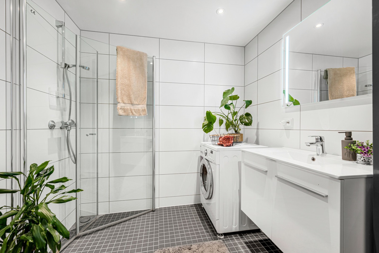 Innbydende bad med flislagte flater og varmekabler i gulv. Opplegg for vaskemaskin. Galleribilde