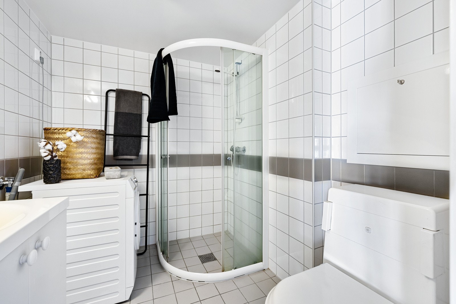 Pent flislagt baderom med termostatstyrte varmekabler, dusjhjørne, benkeskap, servant, speil, toalett samt opplegg for vaskemaskin og tørketrommel. Galleribilde