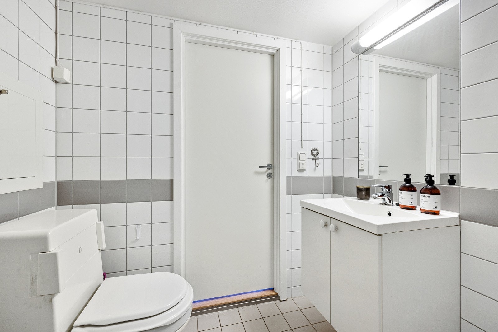 Tidløst utrykk med hvite fliser på vegg og grå fliser på gulv. Galleribilde