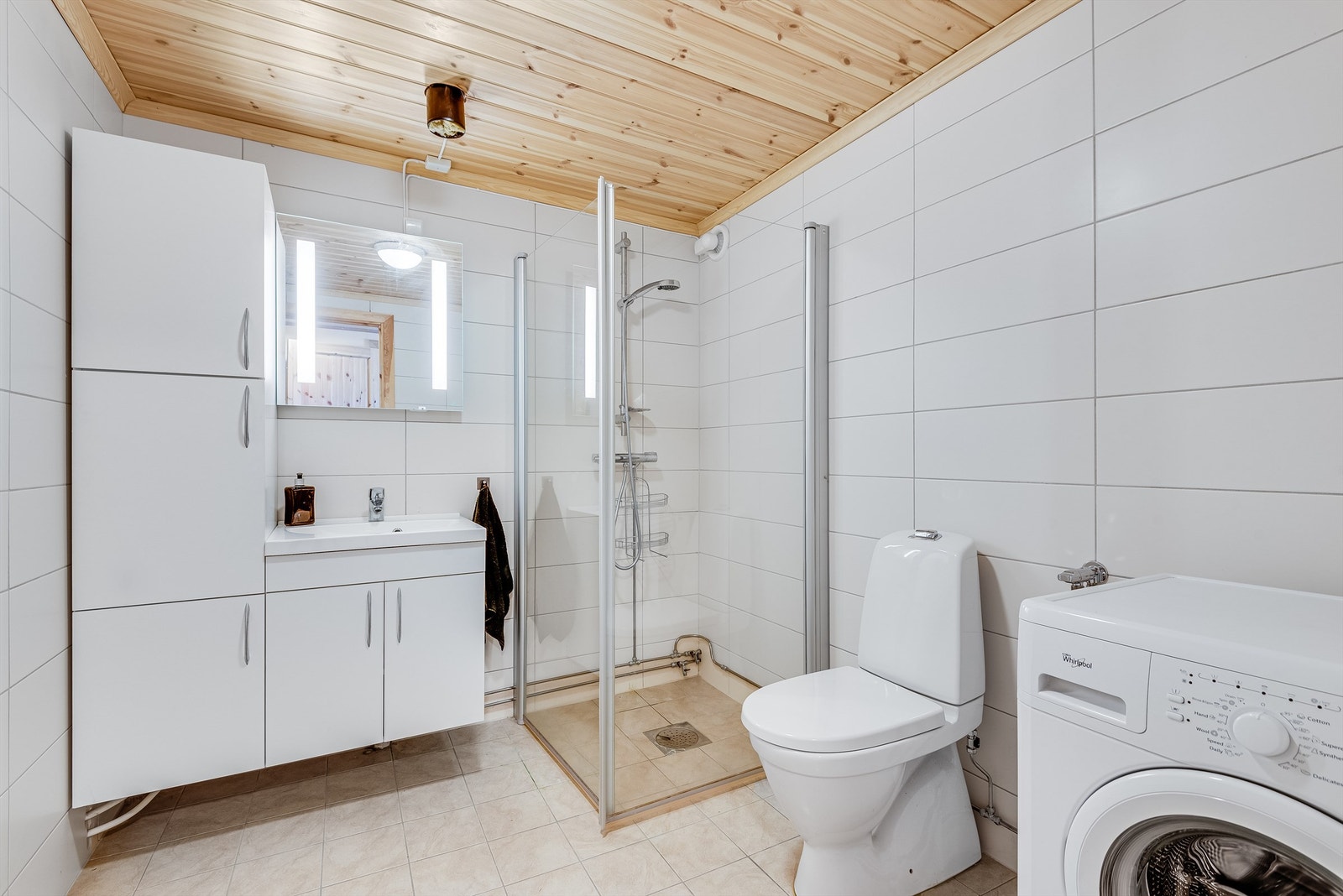 Bad 3 har fliser på gulv og vegger. Det er gulvmontert wc, servant med skapplass og opplegg for vaskemaskin. Galleribilde