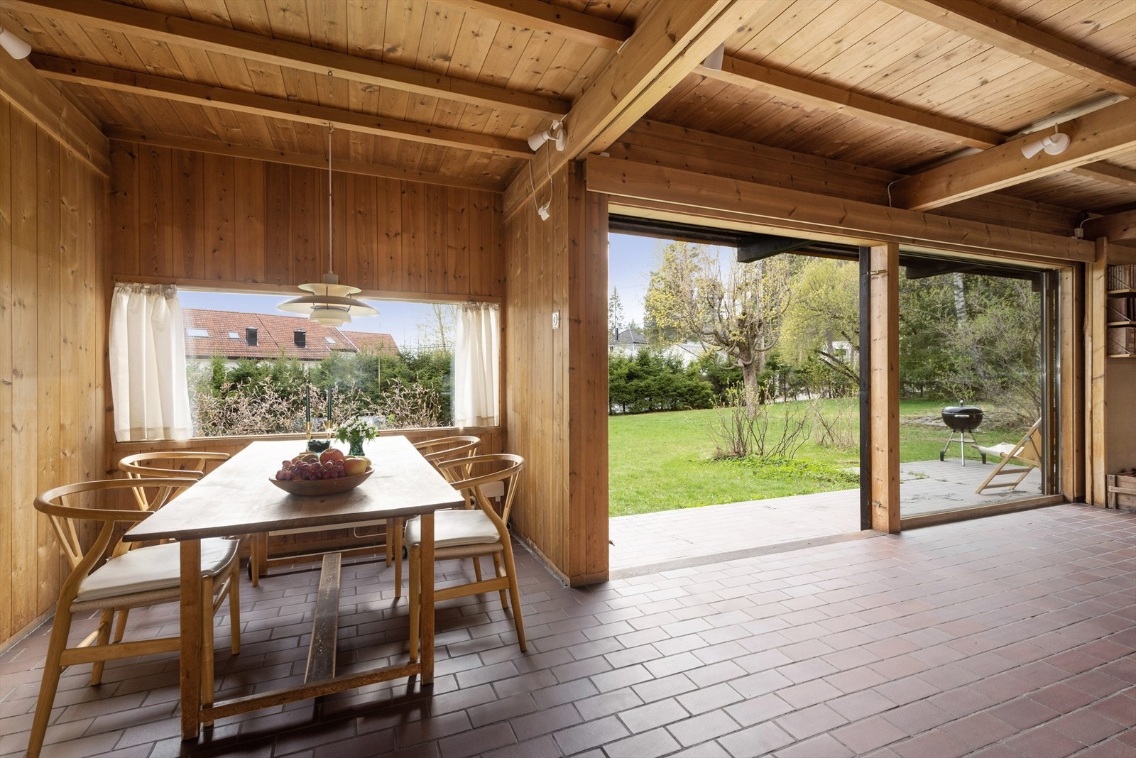 Flislagt uteplatting viderefører stuegulvet ut i hagen. Galleribilde