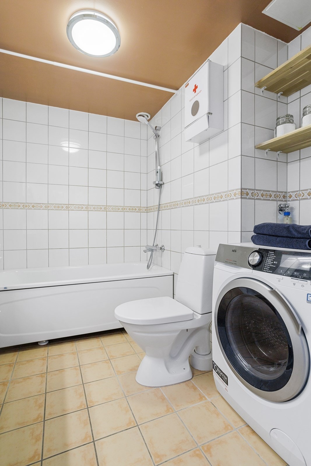 Innredningen består av en toalett, servant med skuffer, speil, belysning og badekar med dusjarmatur. Galleribilde