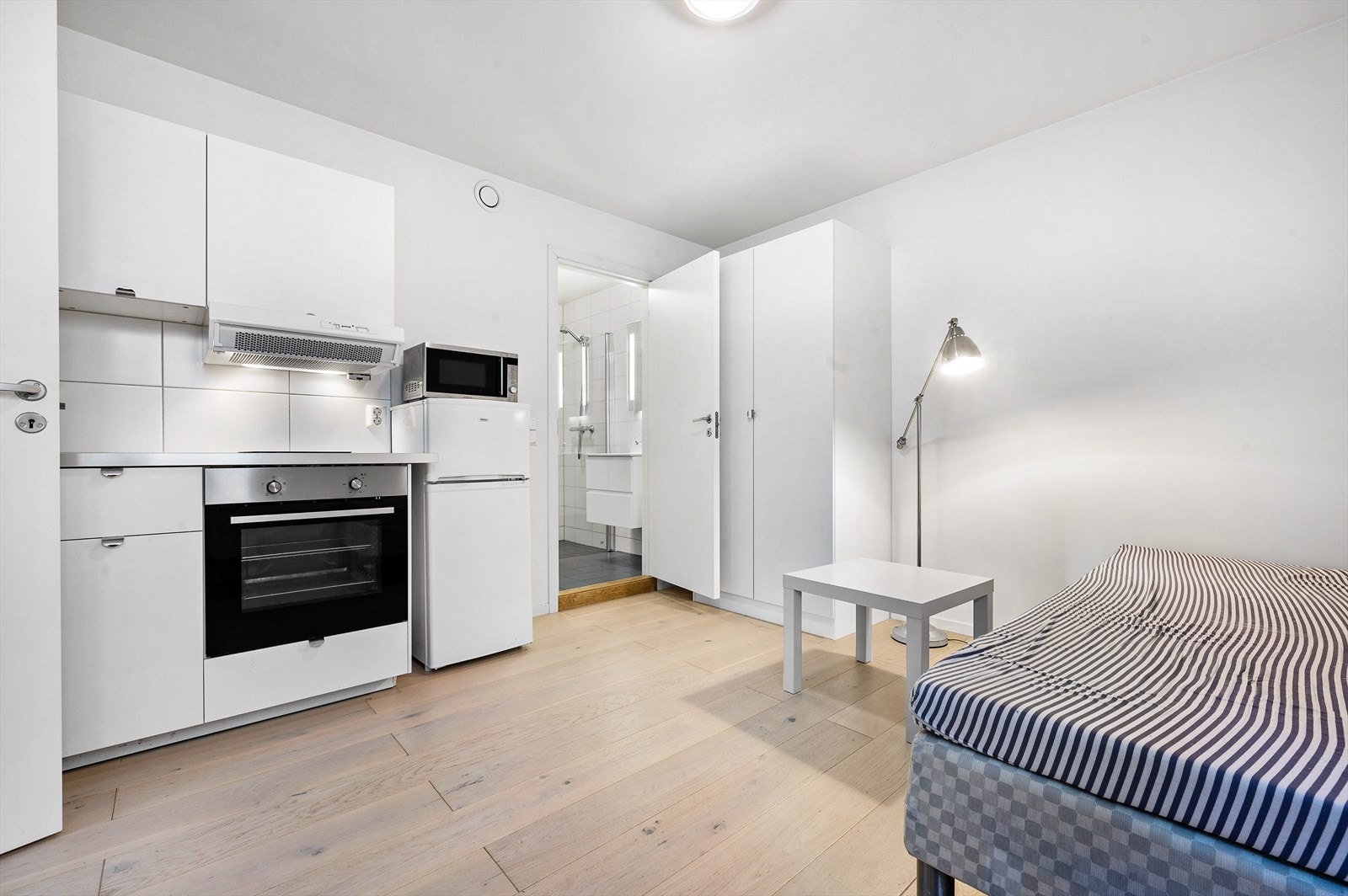 Hybel 1: Rom med hybelkjøkken med underskap og overskap med glatte hvite fronter, samt laminat benkeplate. Integrert stekeovn og kokeplate. Galleribilde