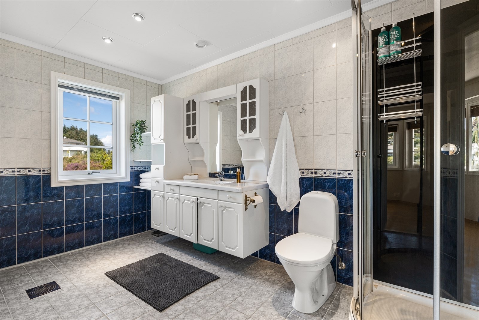 Baderommet er helfliset og har varmekabler i gulvet. Det er innredet med toalett, dusjkabinett og baderomsinnredning med vask. Galleribilde