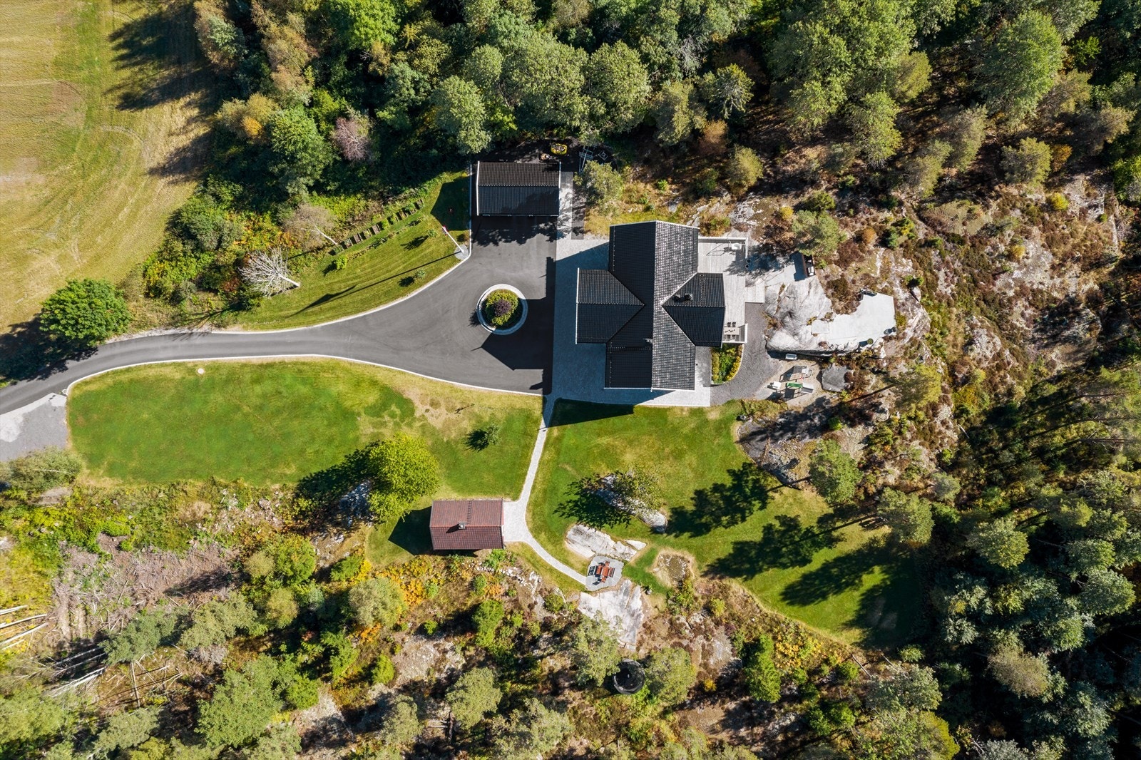 Eneboligen ligger nydelig til for seg selv i skogkanten, omringet av vakkert naturlandskap og en stor, åpen åker ved adkomsten til eiendommen Galleribilde