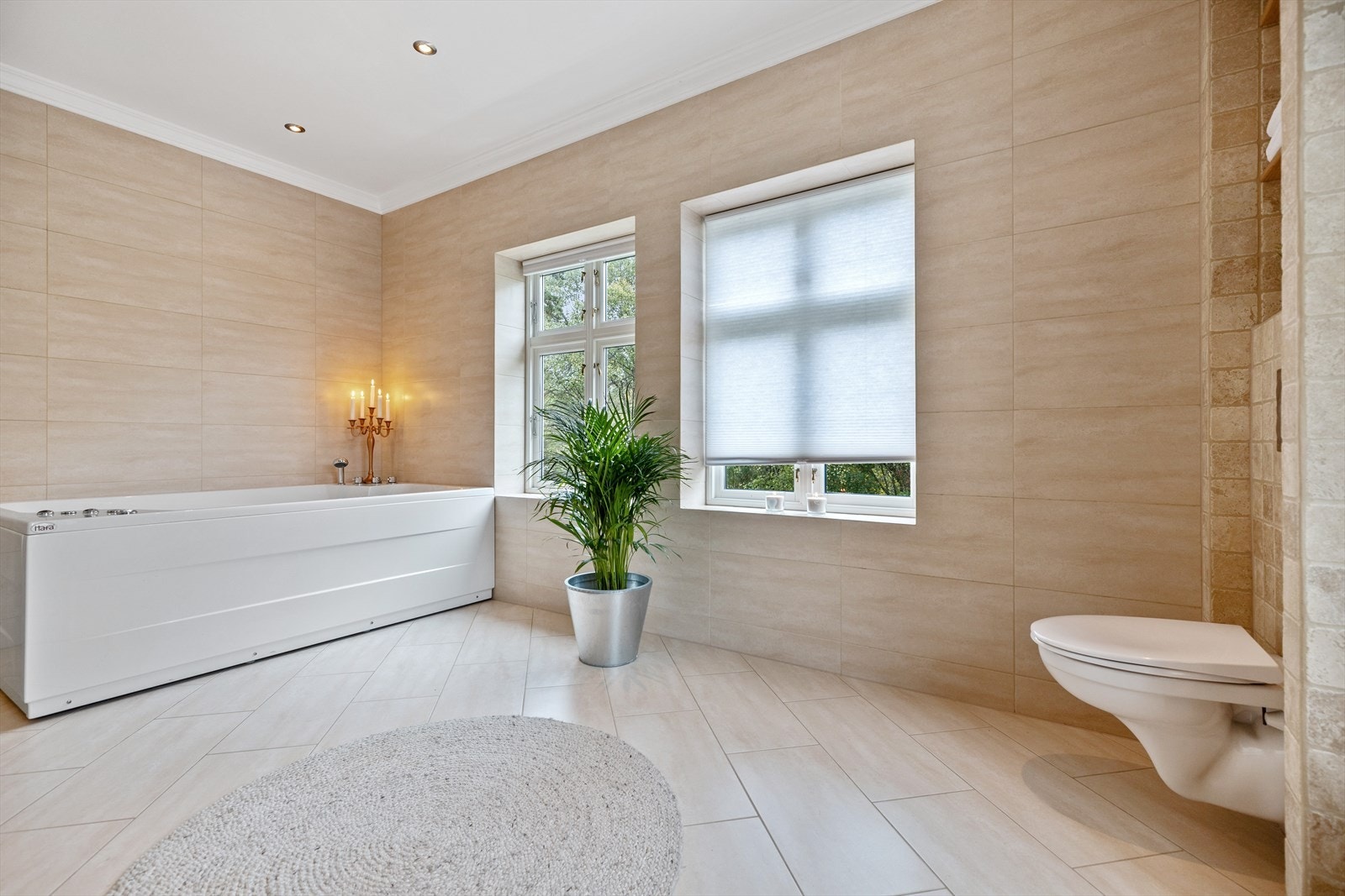 Her får man et stort og lekkert bad med lyse vegg- og gulvfliser. Det er gulvvarme, vegghengt toalett og downlights i himlingen. Galleribilde